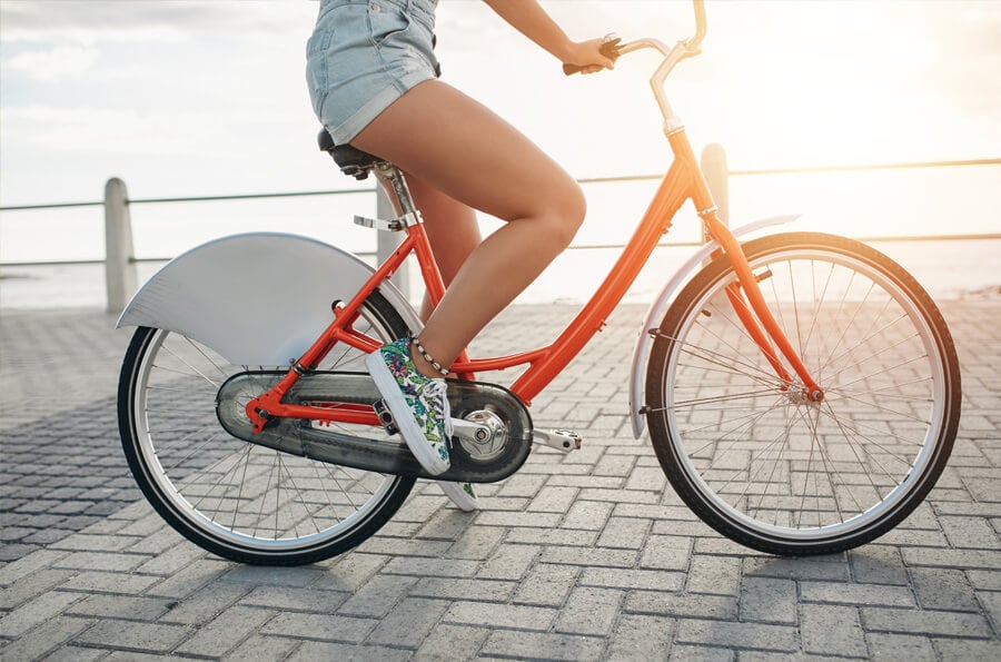 mulher andando de bicicleta em local com sol.