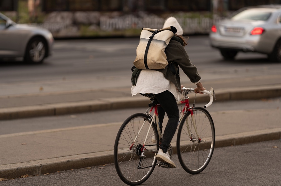 ciclista pedalando com calça e mochila nas costas.