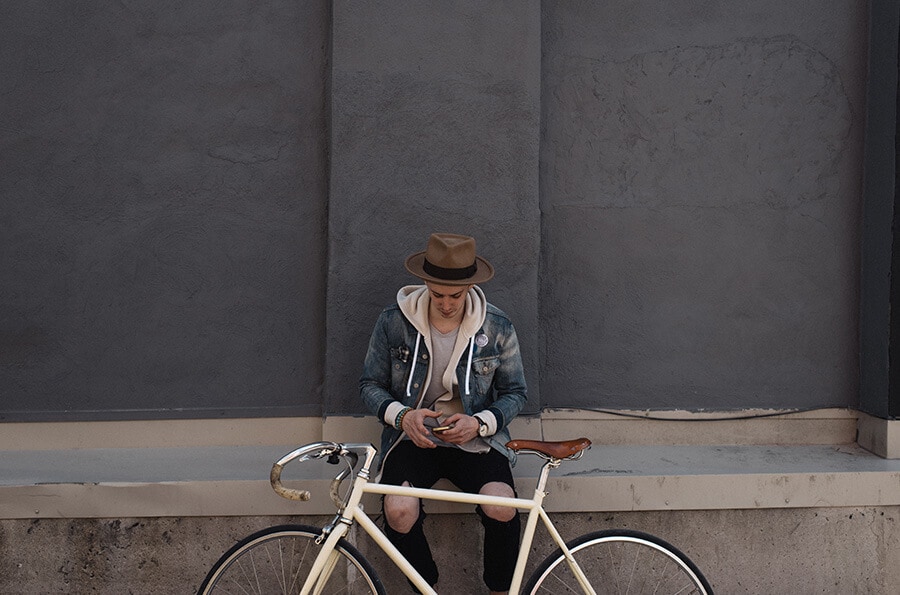 Homem sentando com a bike na sua frente.