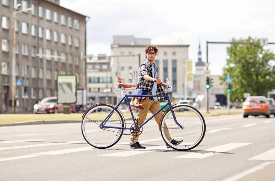 Homem levando a bicicleta na rua.